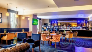 A hotel lobby with a bar area, seating arrangements, and a reception desk. - Colessio (Stirling)