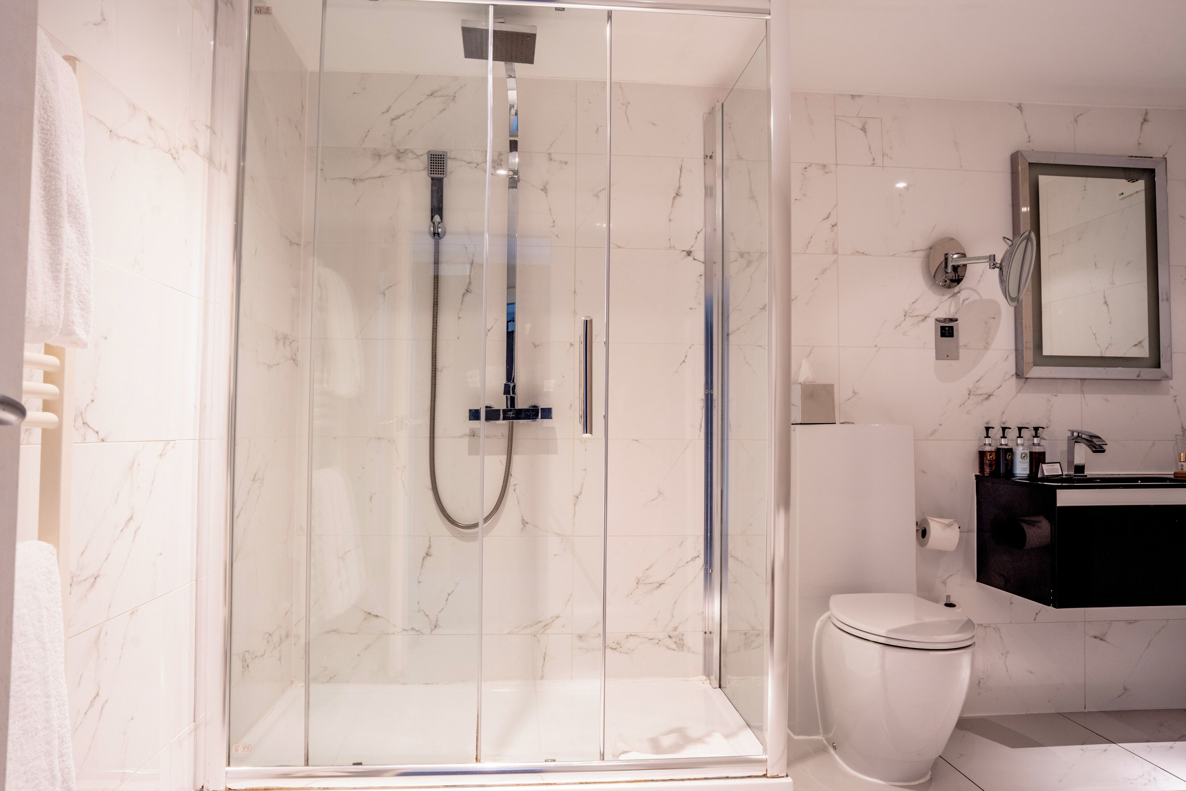 Un bagno moderno con doccia vetro, WC e lavabo con articoli da toilette.