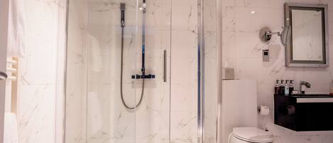 Un bagno moderno con doccia vetro, WC e lavabo con articoli da toilette.