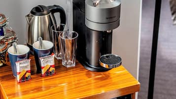 A compact kitchenette with a coffee maker, cups, and a mini-fridge stocked with beverages.