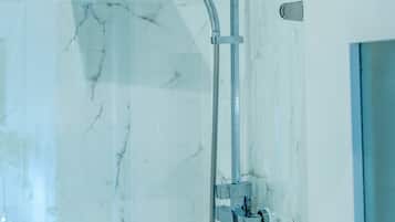 Ein modernes Badezimmer mit einer Glaskabine, Marmorwänden und einer sichtbaren Tür.