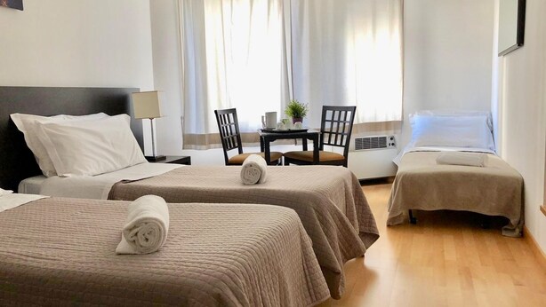 A hotel room with two beds, a desk, a chair, and a table with a plant. - L'Affittacamere di Venezia (Mestre)