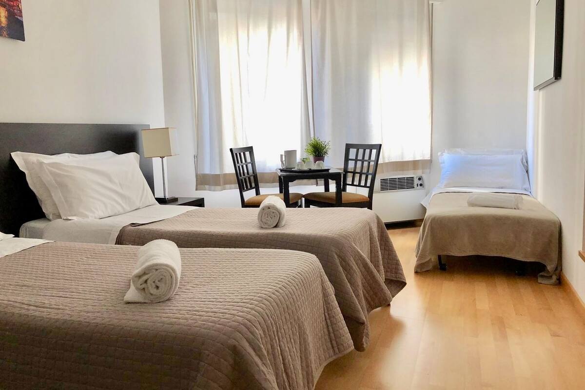 A hotel room with two beds, a desk, a chair, and a table with a plant.