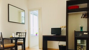A room with a wooden desk, a chair, a television, a mirror, and a door leading to a balcony. - L'Affittacamere di Venezia (Mestre)
