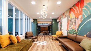 A modern interior with a wooden floor, a brown leather sofa, a green sofa, and a dining area with a table and chairs. - Haka House Wellington (Wellington)