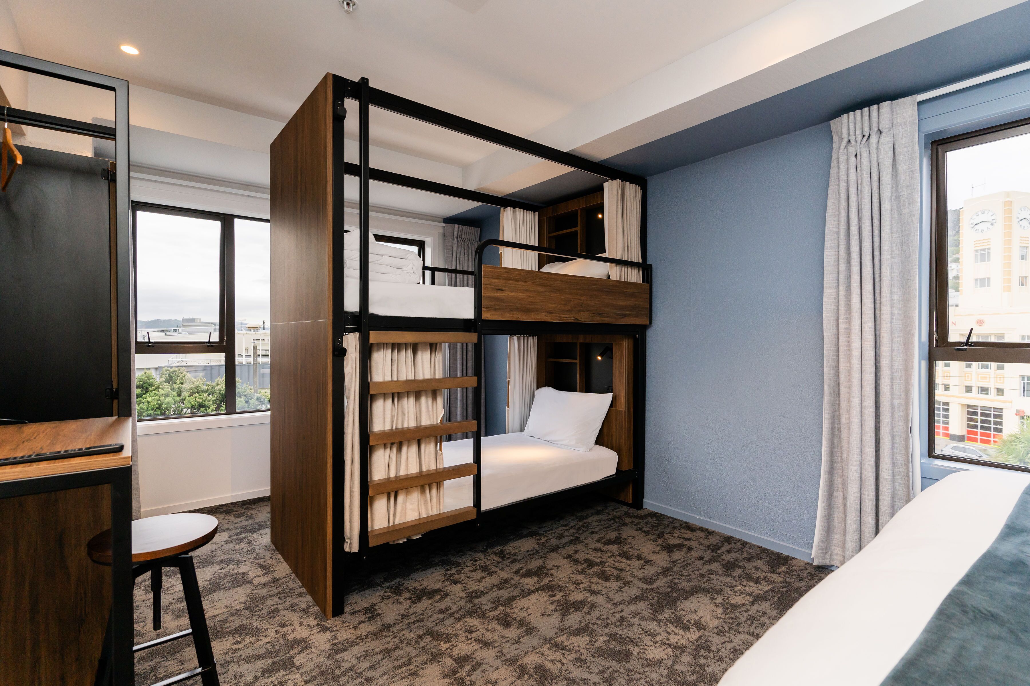Ein Zimmer mit Etagenbett, Schreibtisch und einem fenster mit Vorhängen.