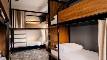 A bunk bed room with a wooden headboard, a ladder, and a curtain.