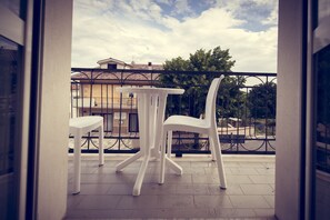 Enjoy a peaceful view from this balcony with a table and two chairs overlooking a residential area with houses and trees.