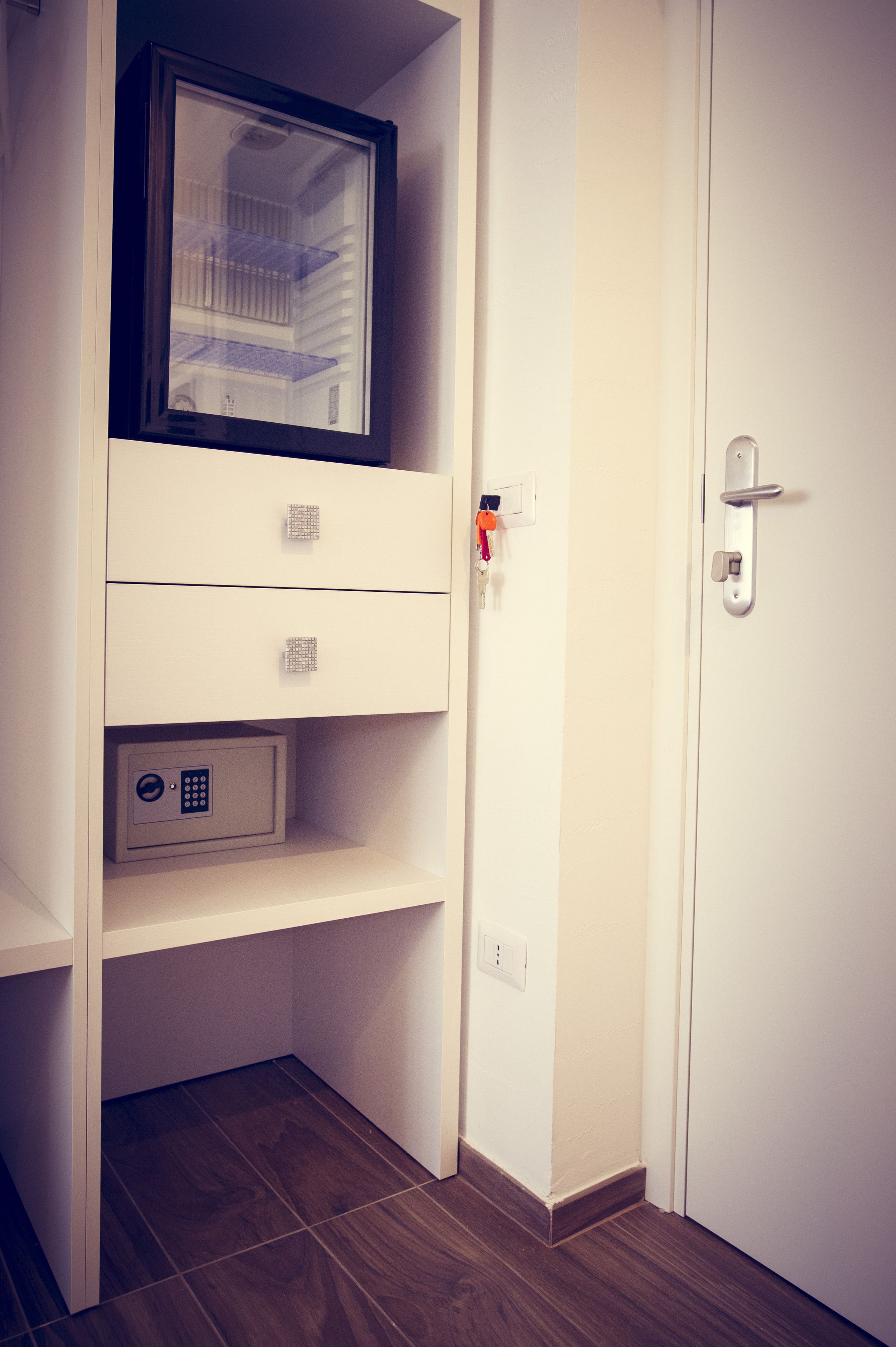 A white room with a door, a safe, and a small window.