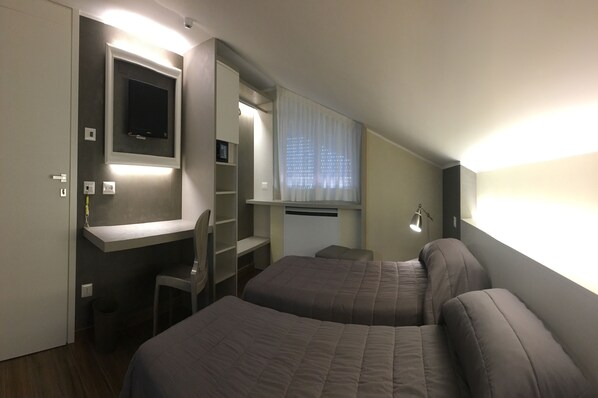 Work and unwind in this stylish room with a desk, two beds, and a wall-mounted TV.