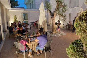 Guests can dine al fresco under shaded tables and umbrellas amidst lush greenery.
