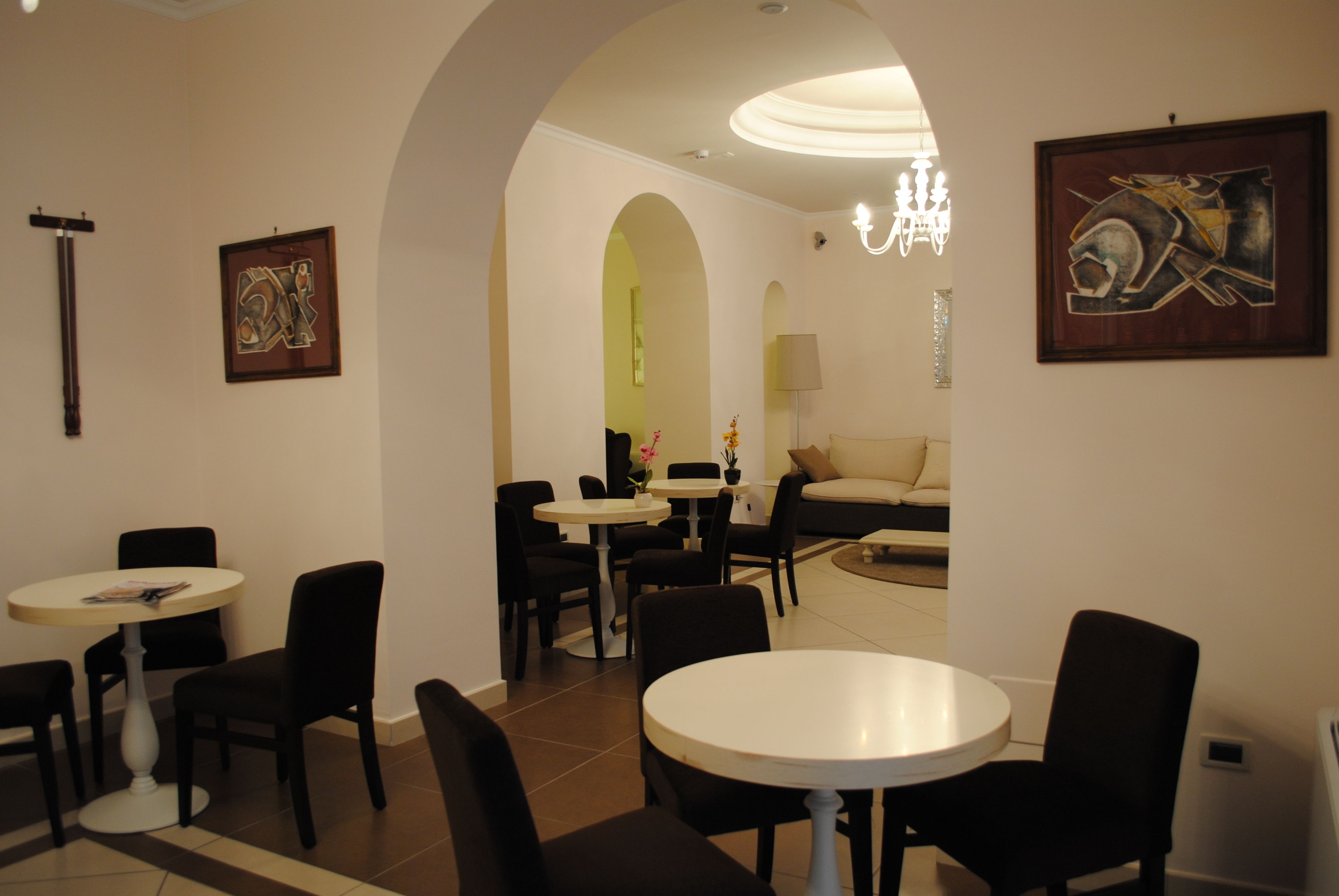 Un área de comedor con mesas y sillas redondas, un sofá y obras de arte en las paredes.