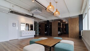 A modern office space with a wooden table, teal and beige chairs, and pendant lighting. - Haka House Auckland City (Auckland)