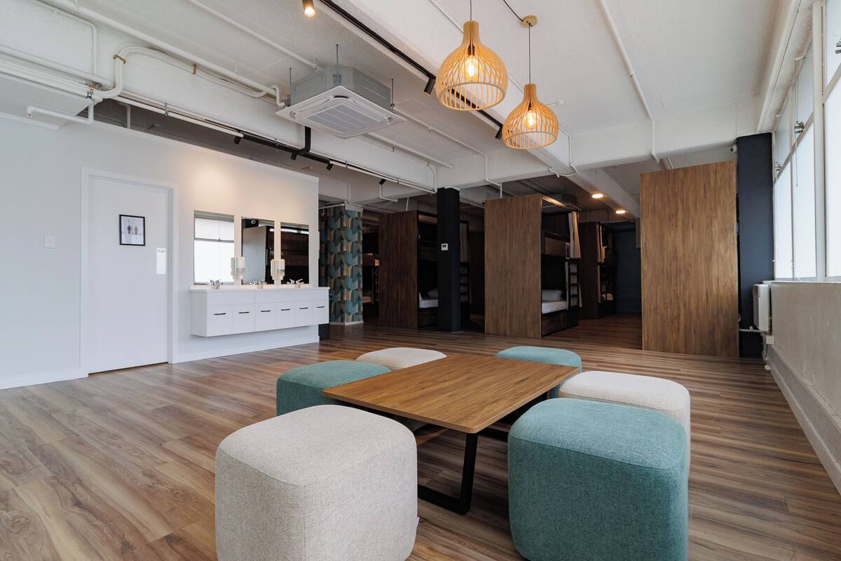 A modern office space with a wooden table, teal and beige chairs, and pendant lighting.