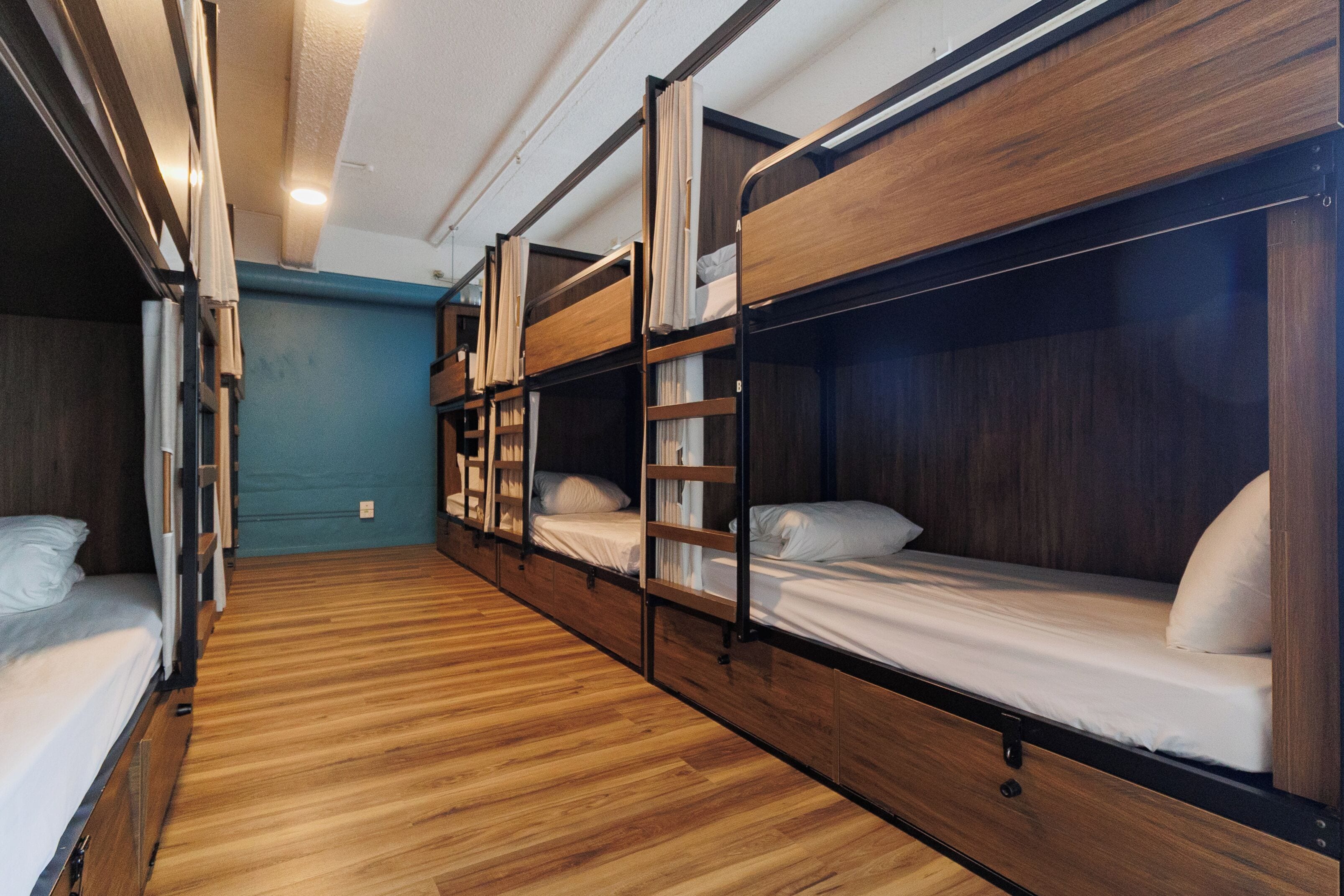 A room with bunk beds, wooden floors, and a blue wall.