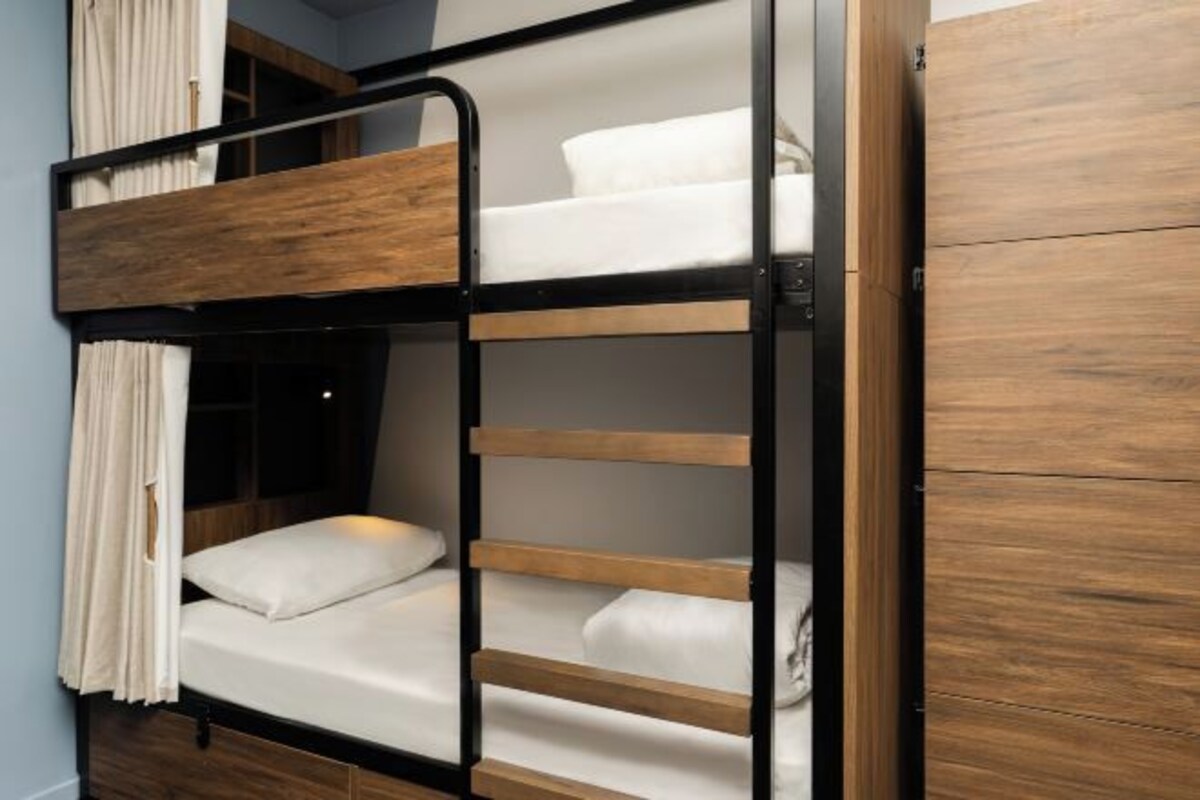 Un lit superposé avec une structure en bois et du linge de lit blanc.