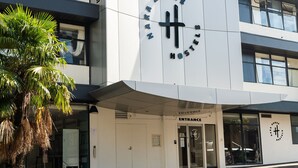 A modern building with a large logo, a visible entrance, and a palm tree in front. - Haka House Auckland City (Auckland)