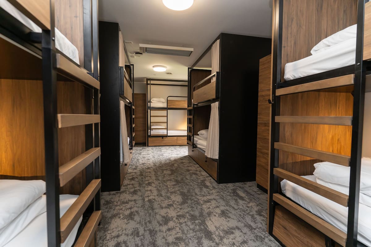 A narrow hallway with bunk beds on both sides, leading to a room with a bunk bed in the center.