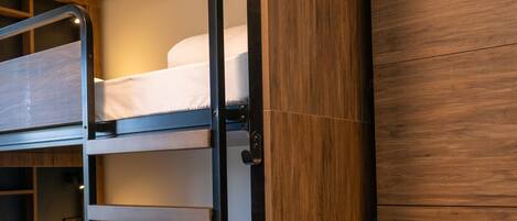 A bunk bed with a wooden wardrobe beside it.