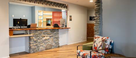 Un área de recepción con pared de piedra, piso de madera y una silla colorida.