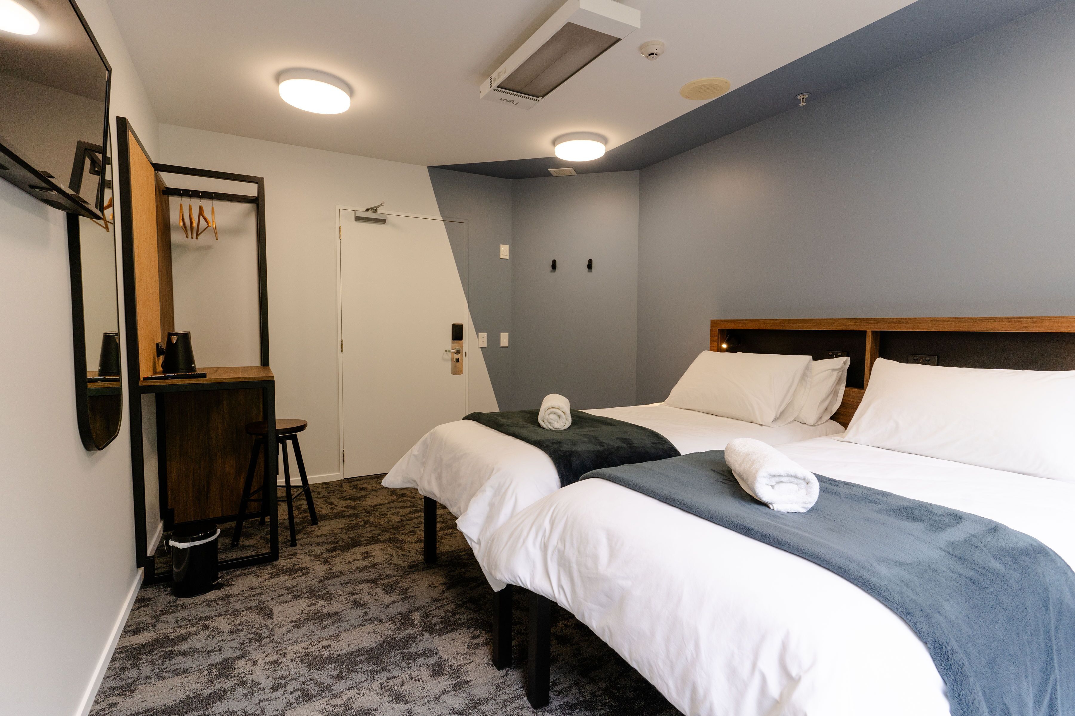 Een hotelkamer met twee bedden, een bureau en een spiegel.