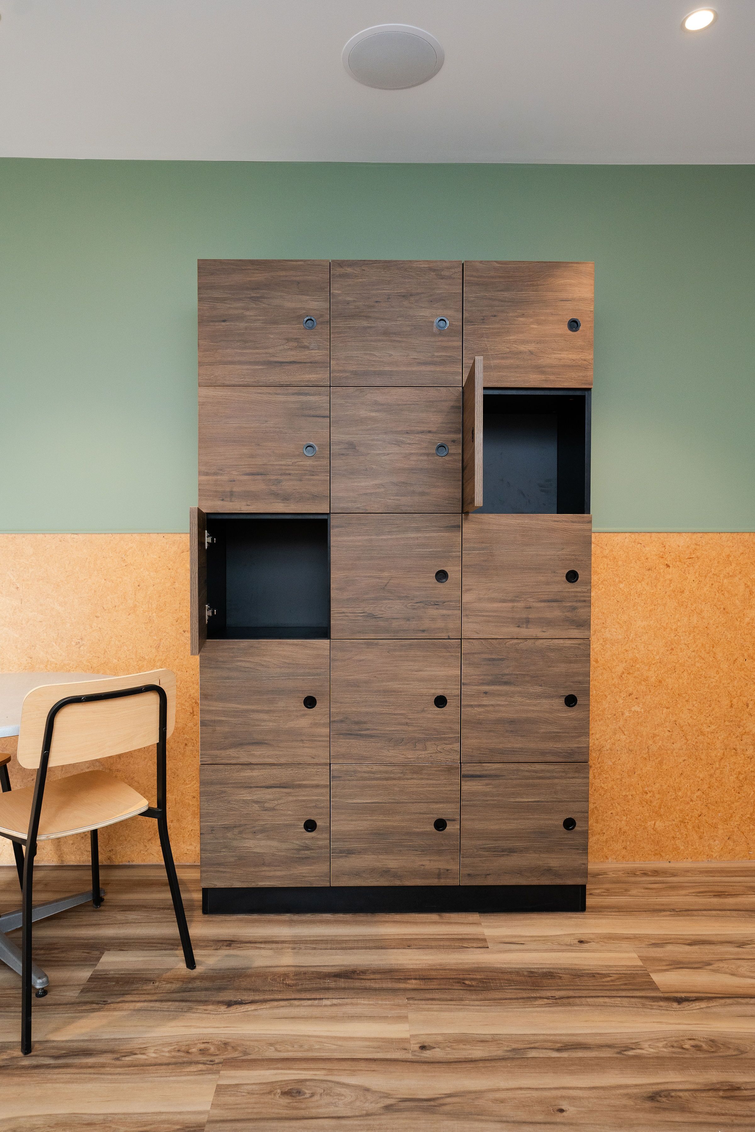 A room with a wooden wardrobe, a chair, and a table.