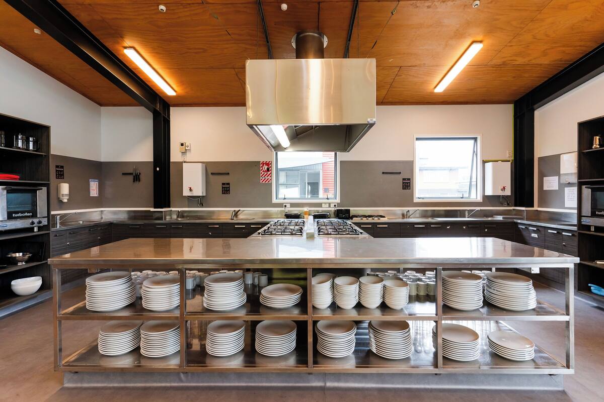 Una cocina moderna con electrodomésticos de acero inoxidable, una isla central con platos apilados y un techo de madera.