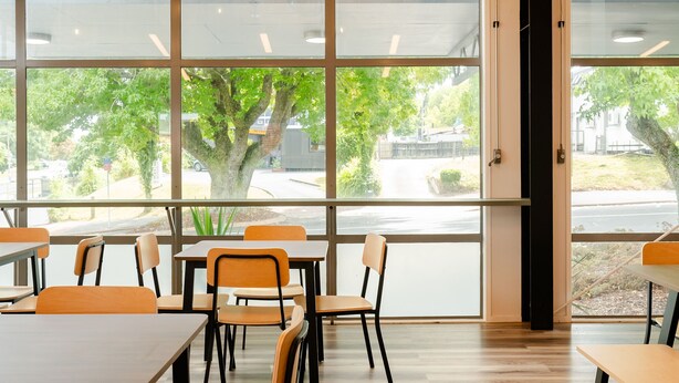 A spacious room with large windows, wooden flooring, and orange chairs. - Haka House Rotorua (Rotorua)