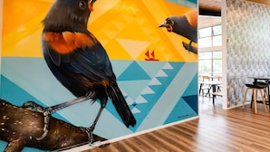 A mural of birds on a wall with geometric patterns and a wooden ceiling. - Haka House Rotorua (Rotorua)