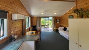 A cozy cabin-style room with a dining area, a sofa, and a kitchenette. - Off The Beaten Trail Accommodation & Bike Tours (Murchison)