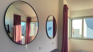 A room with two round mirrors on the wall, a window with curtains, a sofa, and a bed. - YHA Nelson - Backpackers (Nelson)