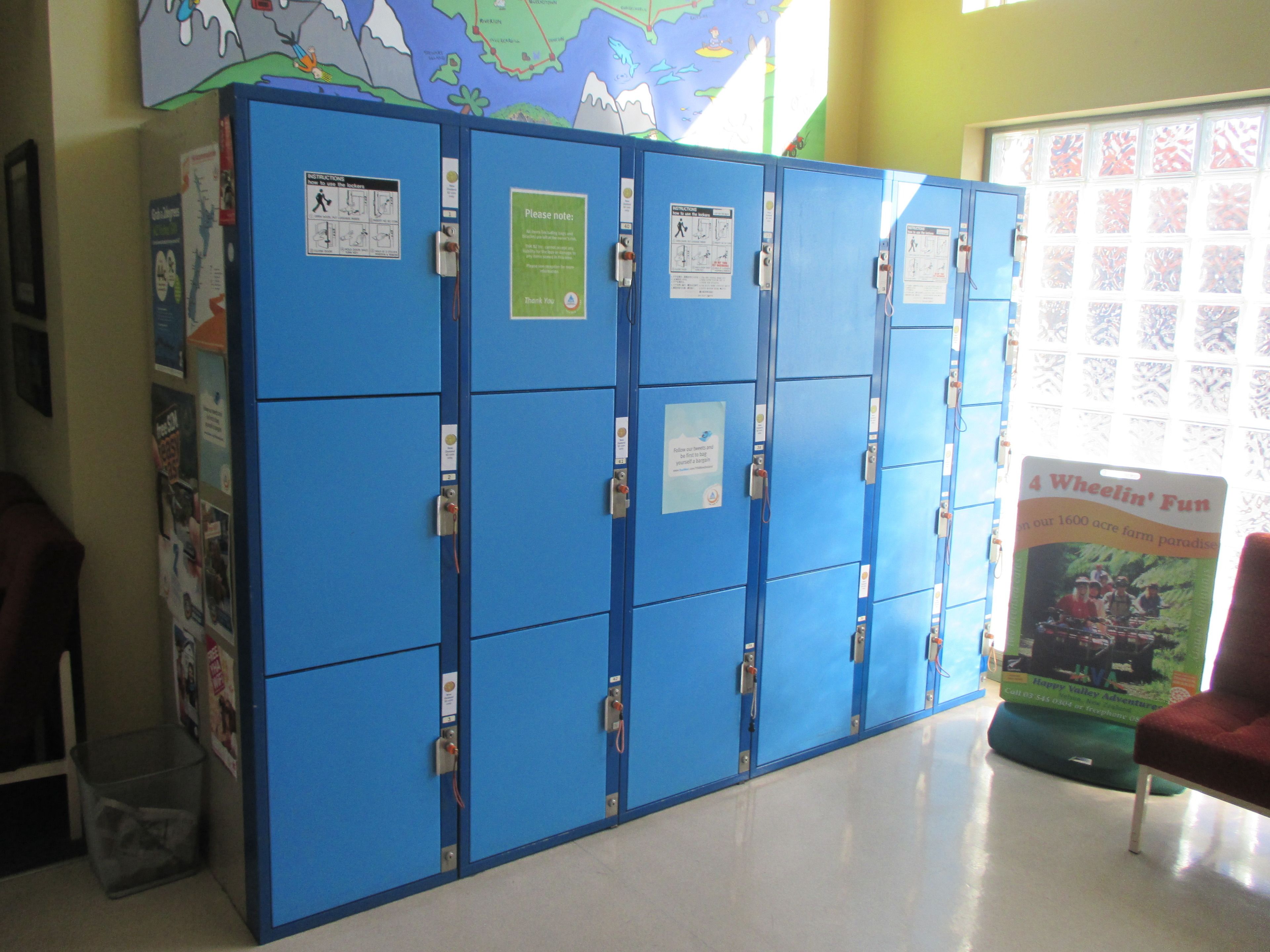 A row of blue lockers with various notices and a map on the wall behind them.