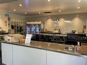 A modern kitchen with stainless steel appliances, a freezer, and a sign indicating kitchen cleaning times. - YHA Nelson - Backpackers (Nelson)