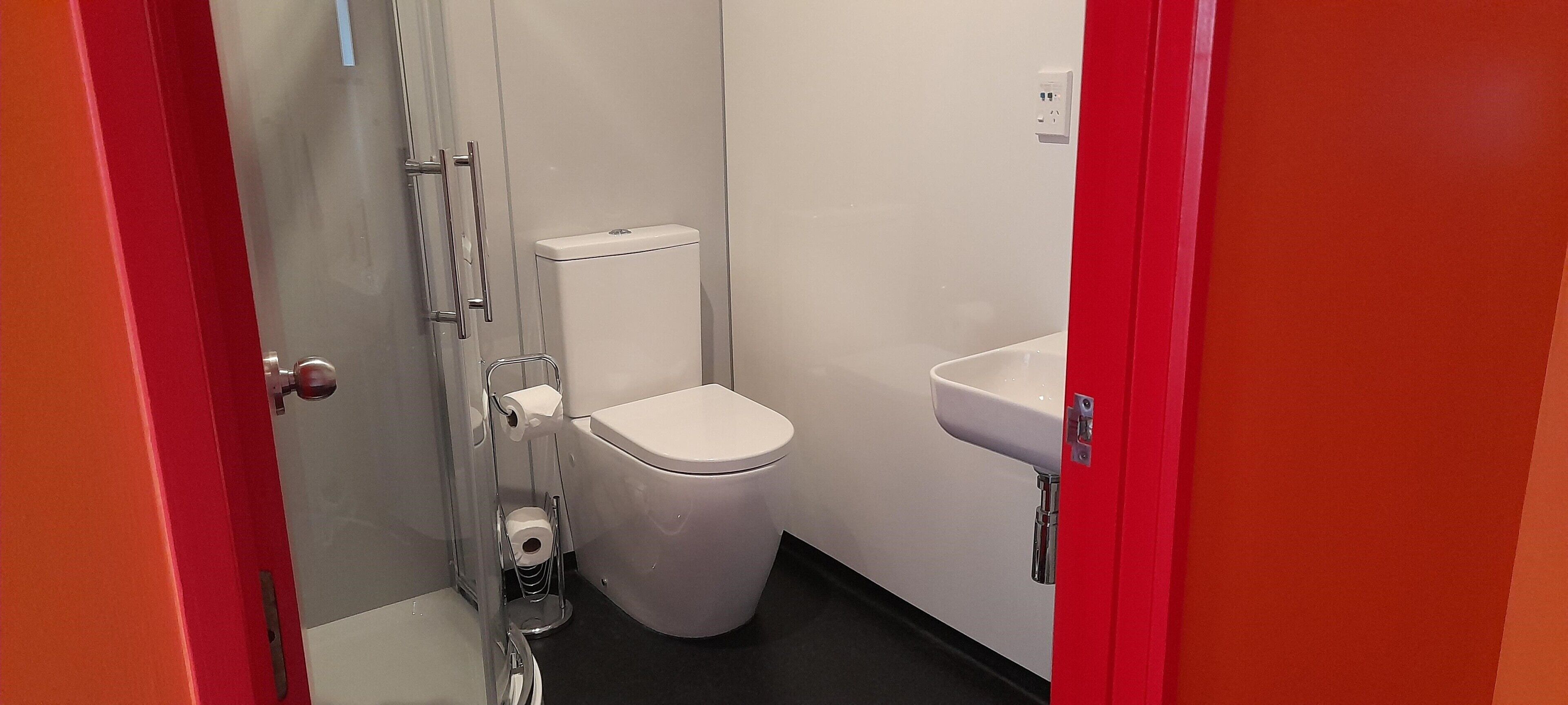 A small, compact bathroom with a white toilet, a sink, and a shower area.