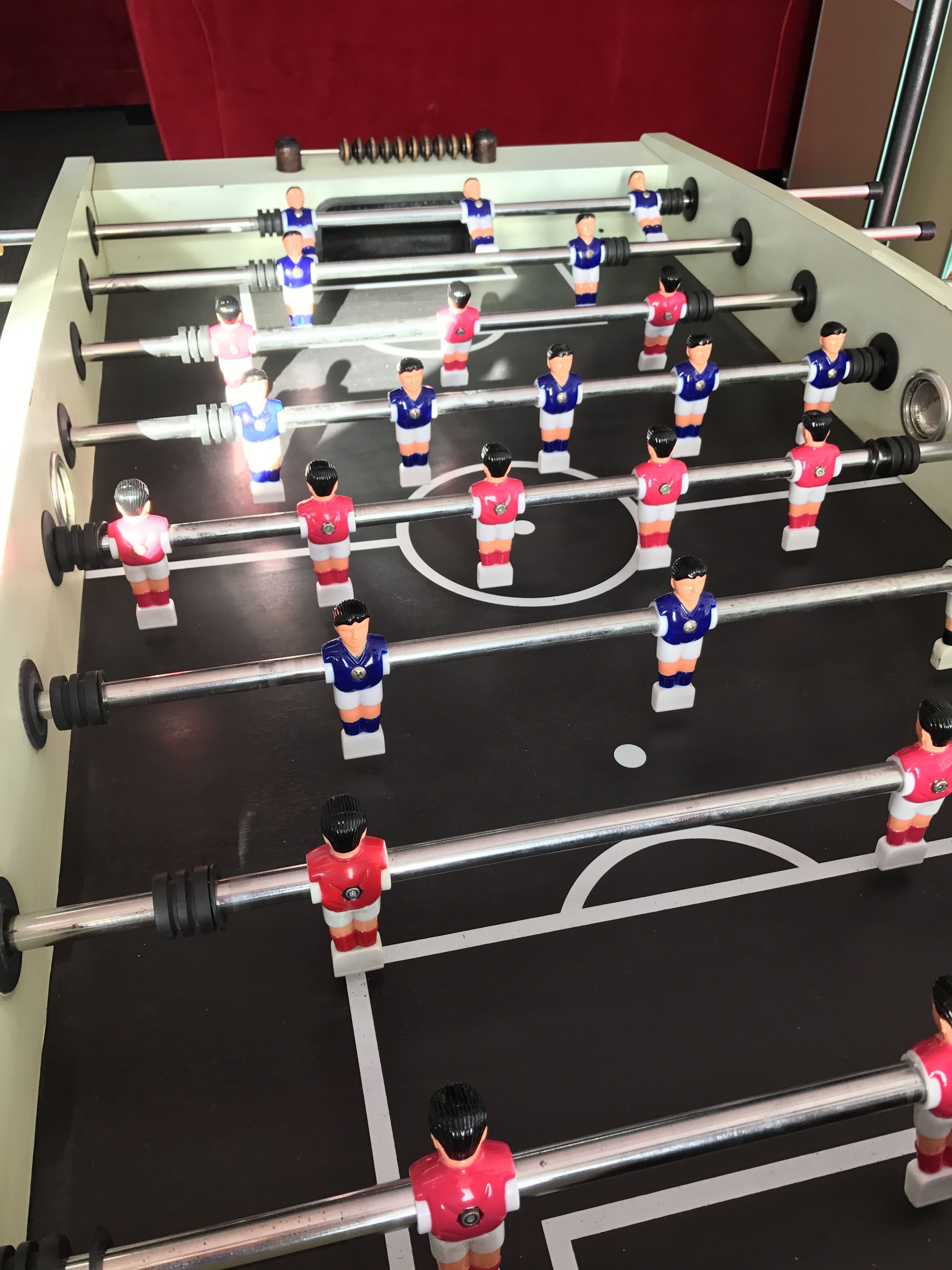 A foosball table with player figures in red and blue uniforms.