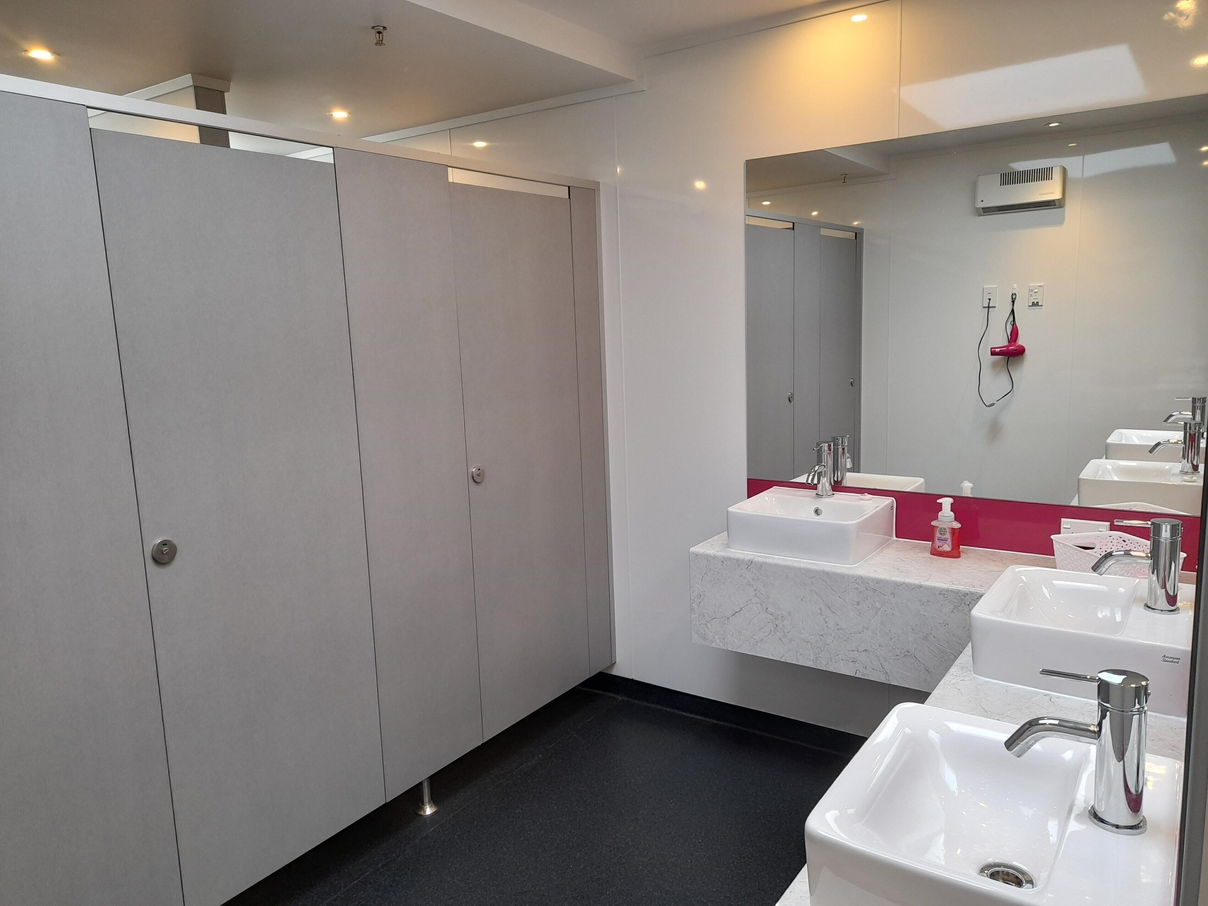 Un baño moderno con un espejo grande, dos lavamanos y una cabina de ducha a pie.