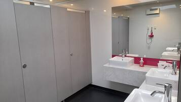 Un baño moderno con un espejo grande, dos lavamanos y una cabina de ducha a pie.