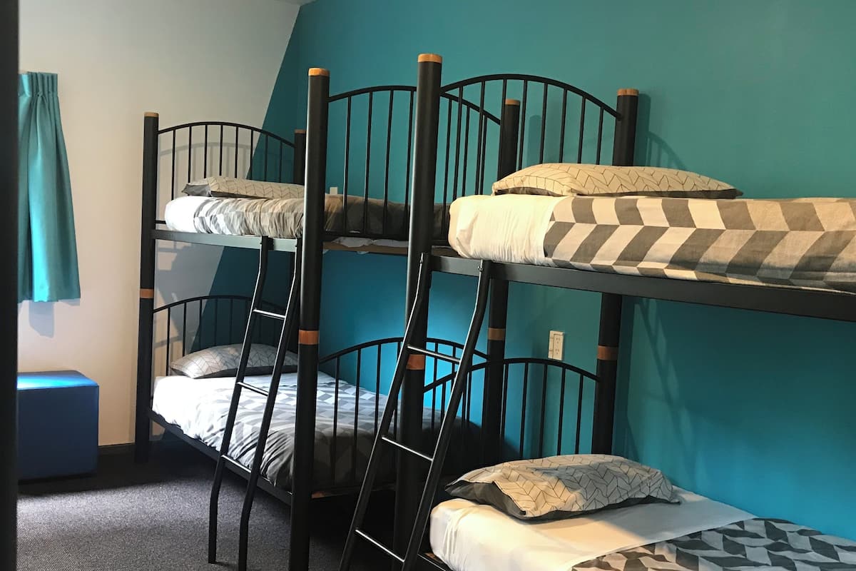 A bunk bed room with a blue wall, a small blue bench, and a ladder.