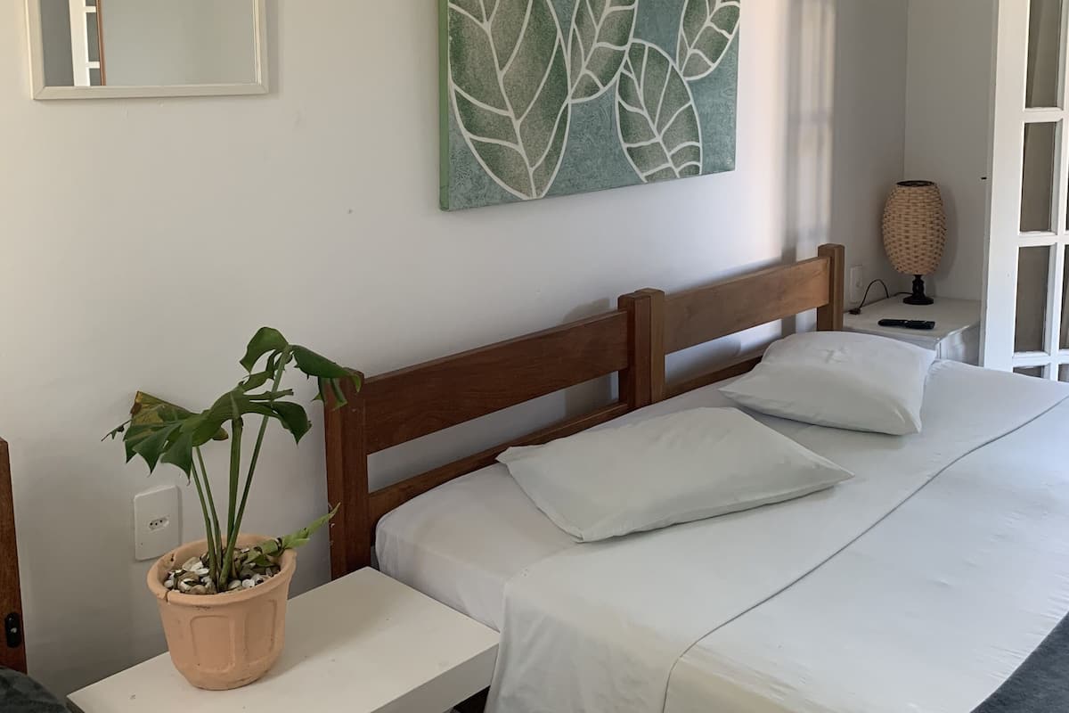 A bedroom with a bed, bedside table, and a potted plant.
