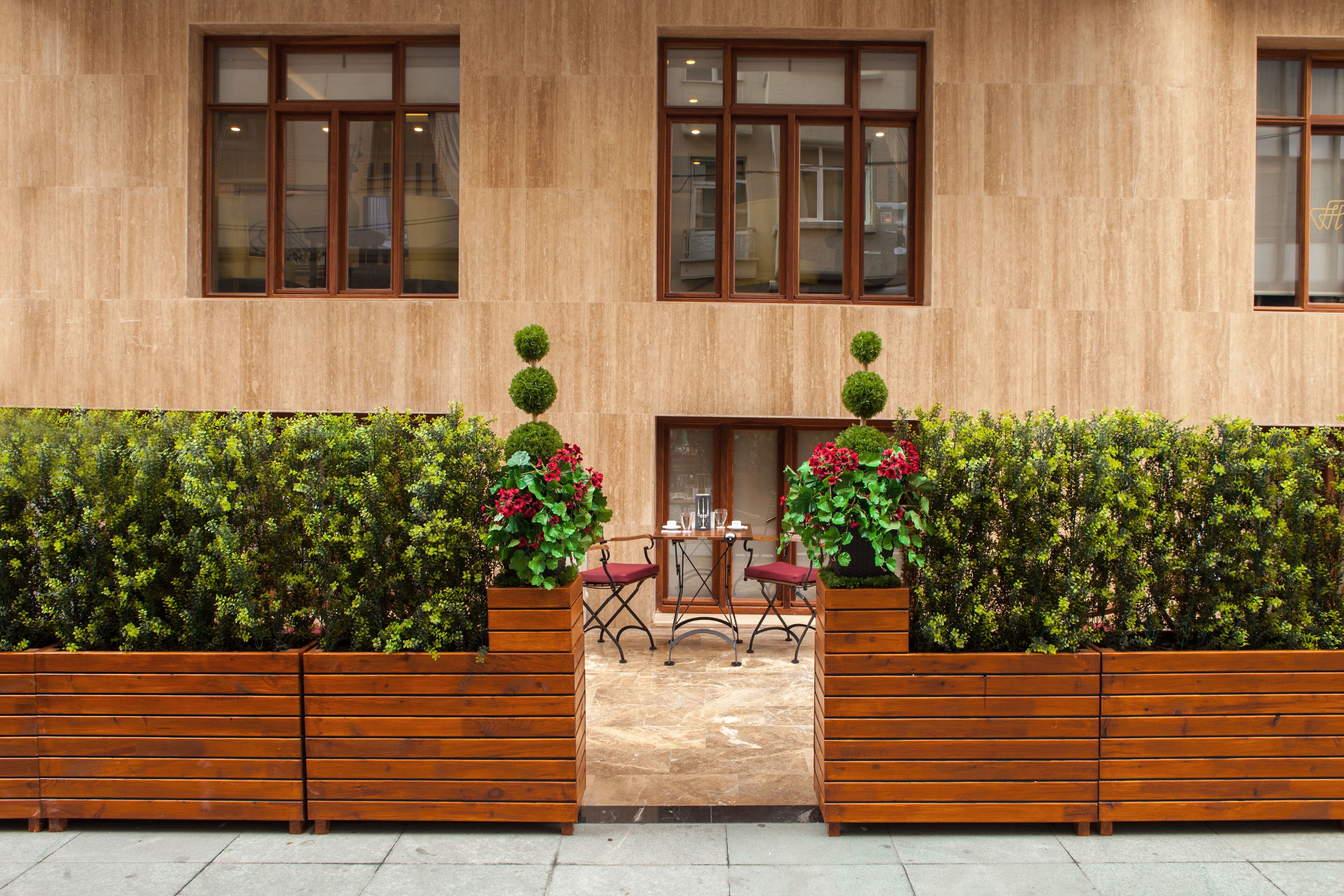 Ein Gebäude mit Holzfassade, zwei Fenstern und einer kleinen Terrasse mit Tisch und Stühlen.