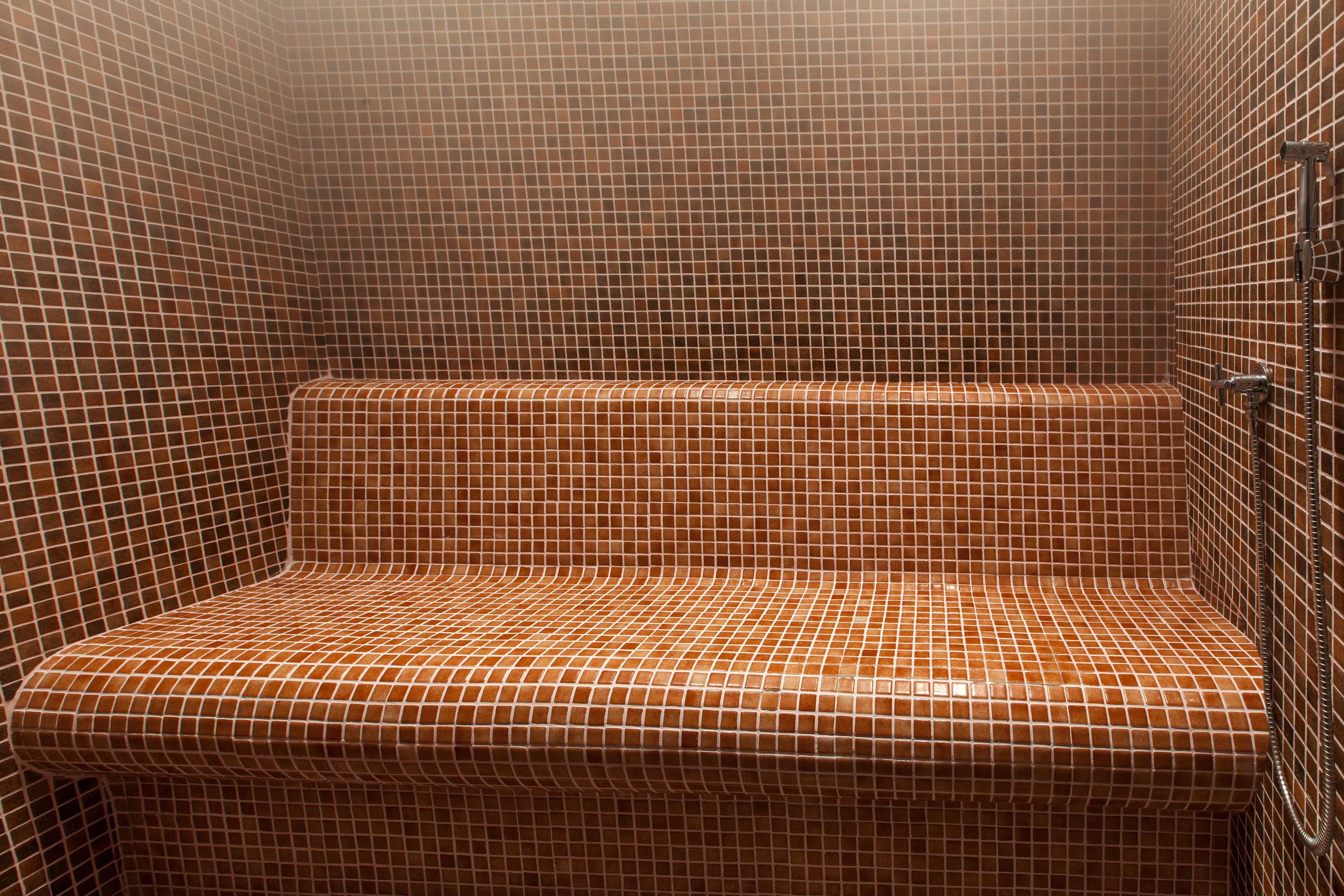 A tiled shower area with a bench.