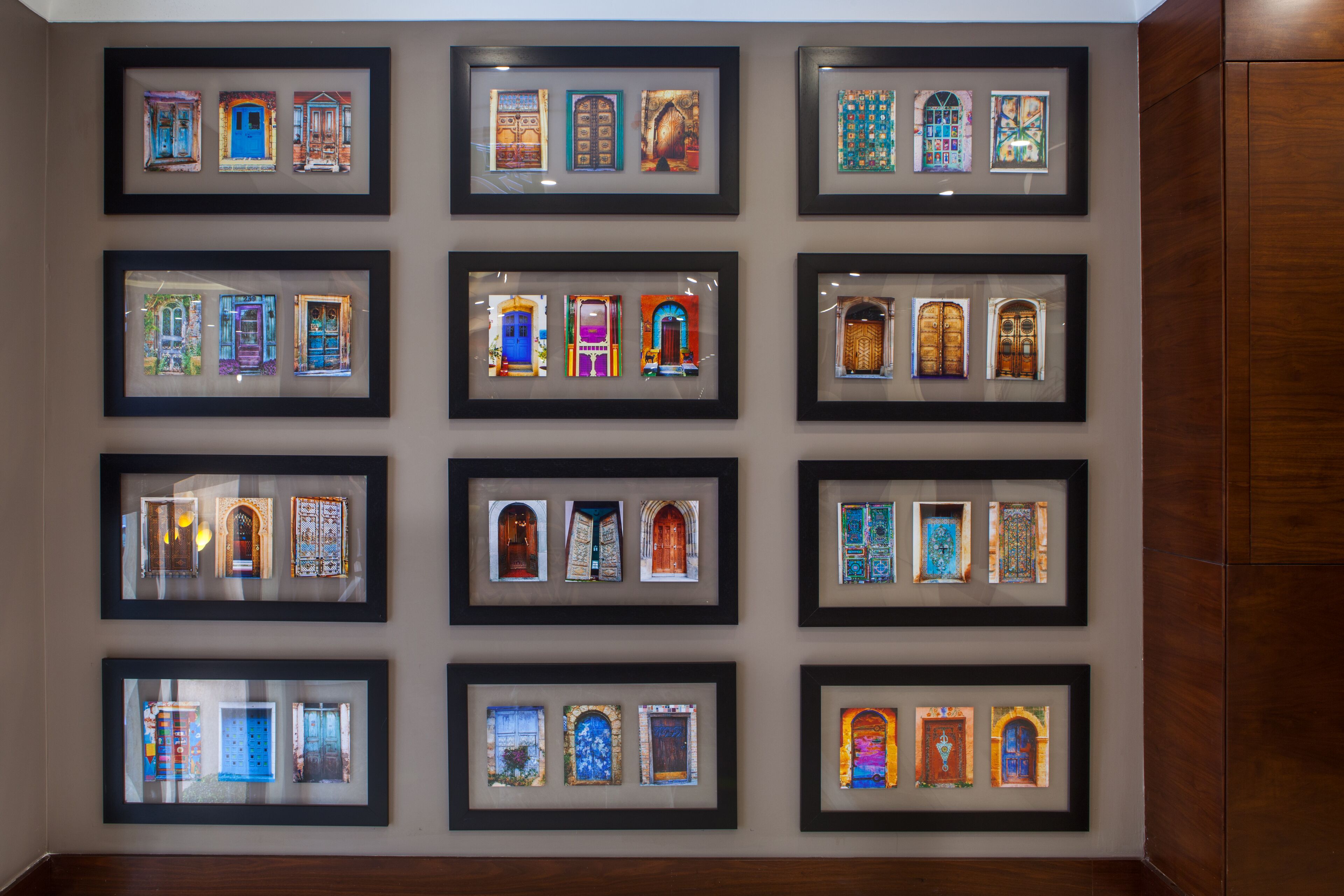 A wall with multiple framed pictures of doors and windows.