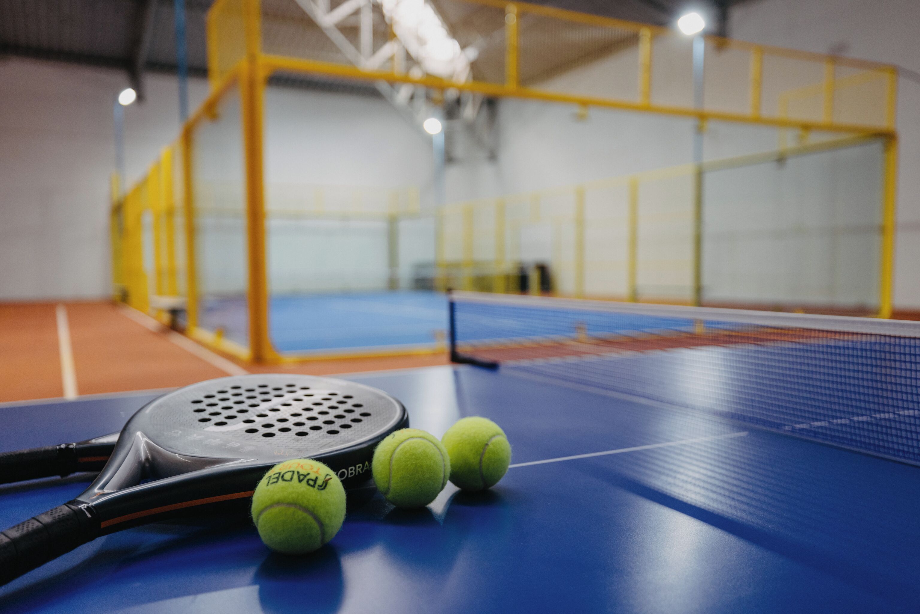 Ein Tennisplatz mit Netz, Tennisschläger und drei Tennisb ällen.