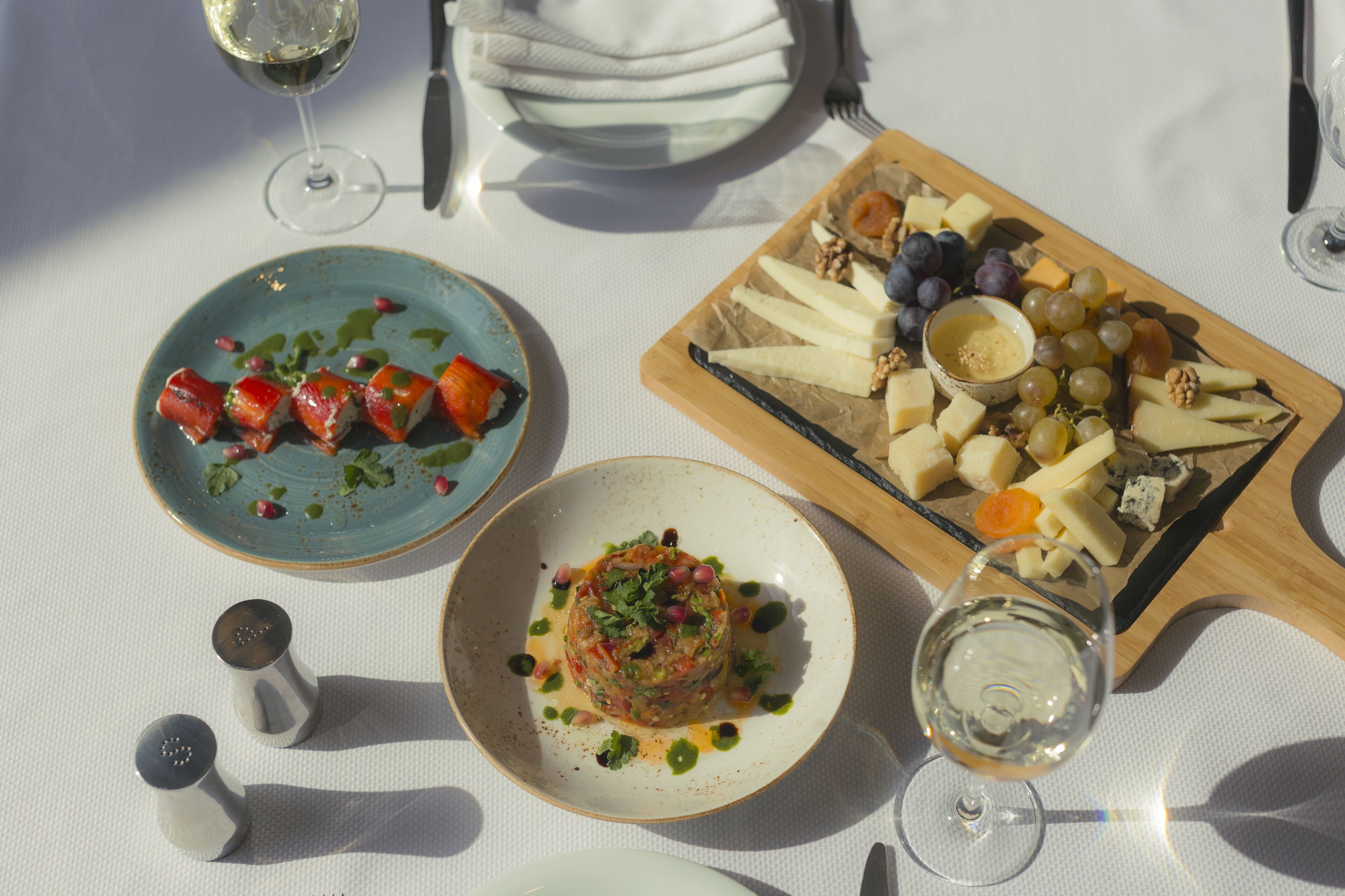 A table set with a variety of cheeses, grapes, and a dish of diced fruit.
