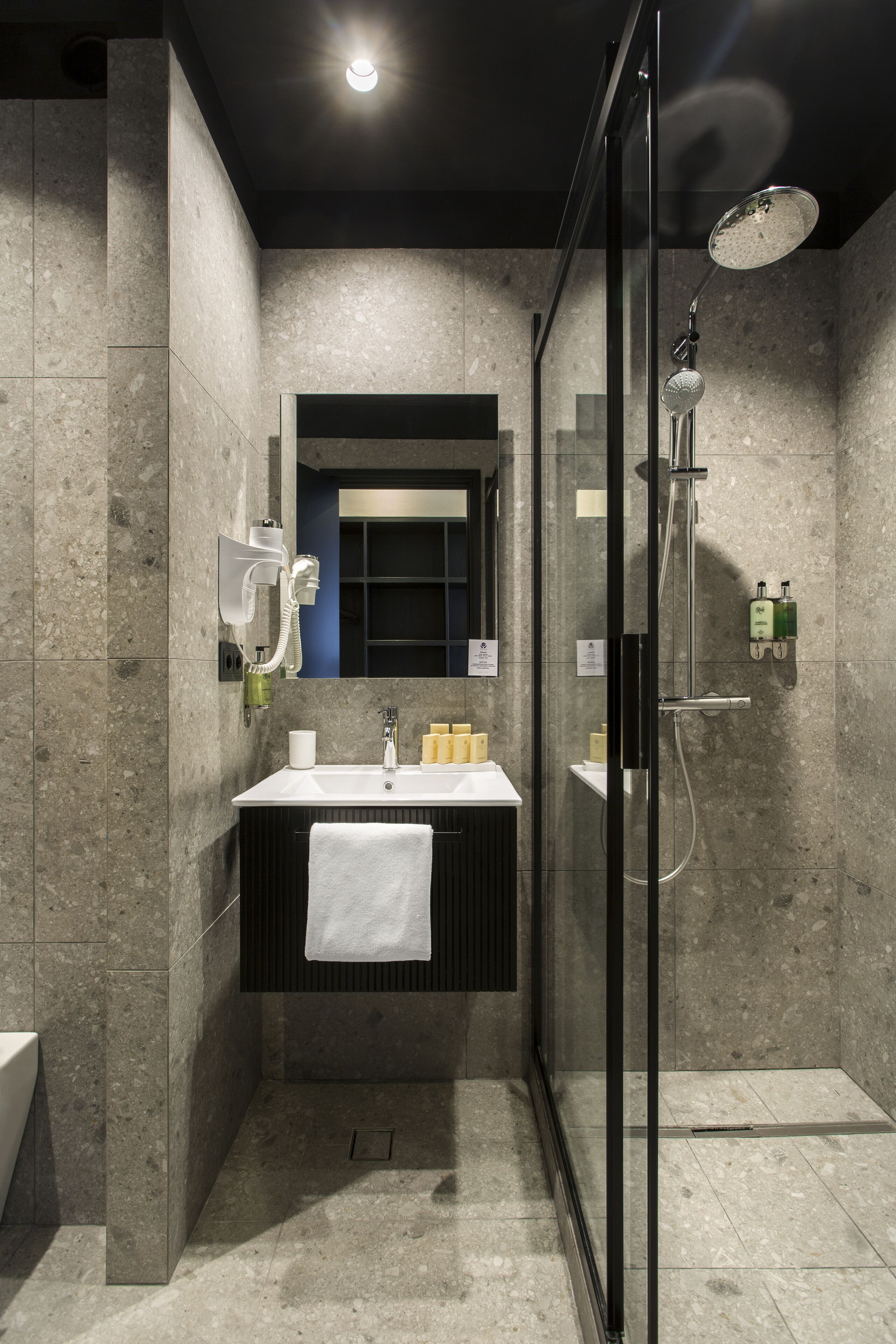 Une salle de bain moderne avec une douche à parois de verre, un meuble-lavabo avec une serviette et un miroir au-dessus du lavabo.