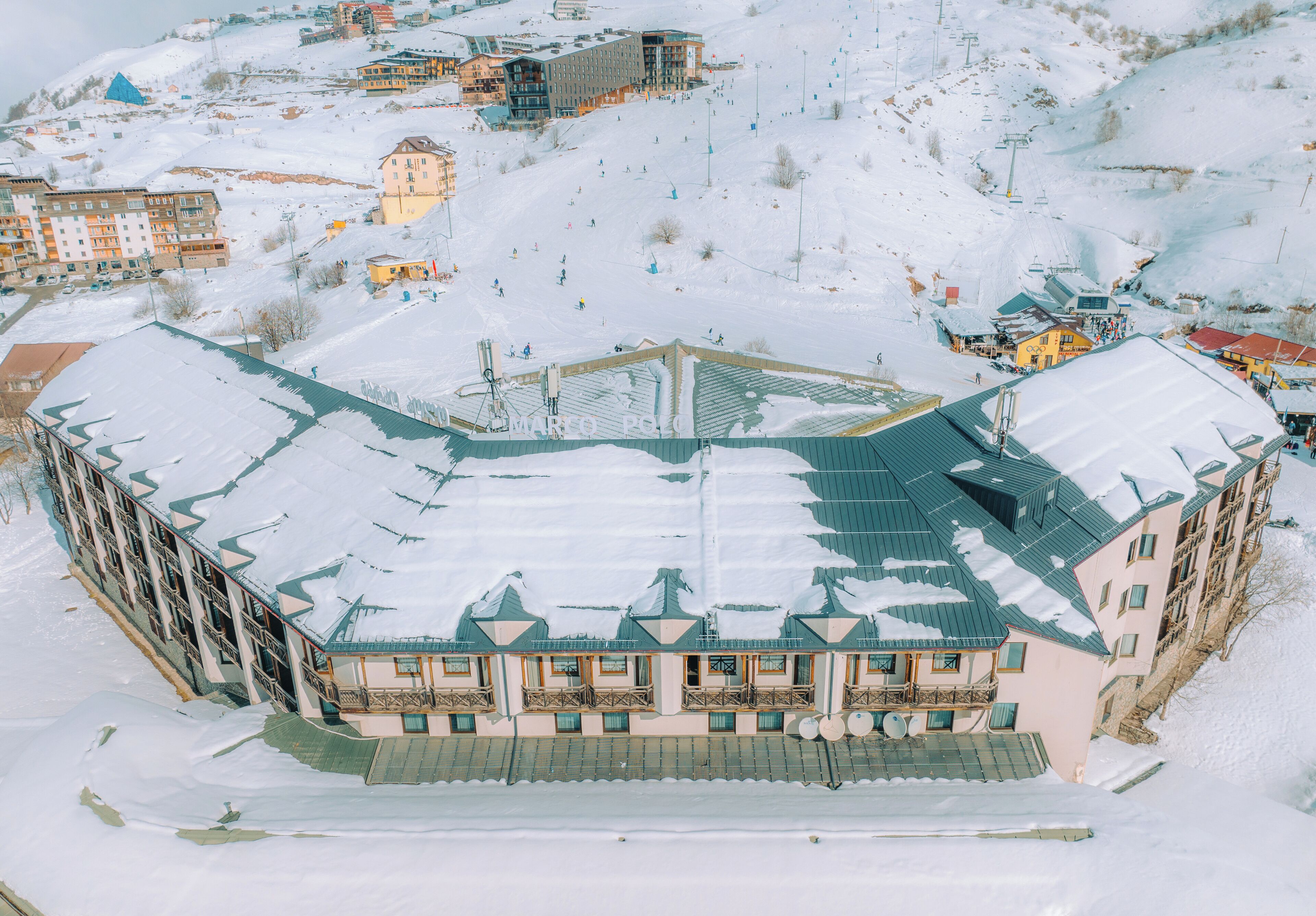 Ein großes Gebäude mit mehreren Balkonen und einem mit Schnee bedeckten Dach.