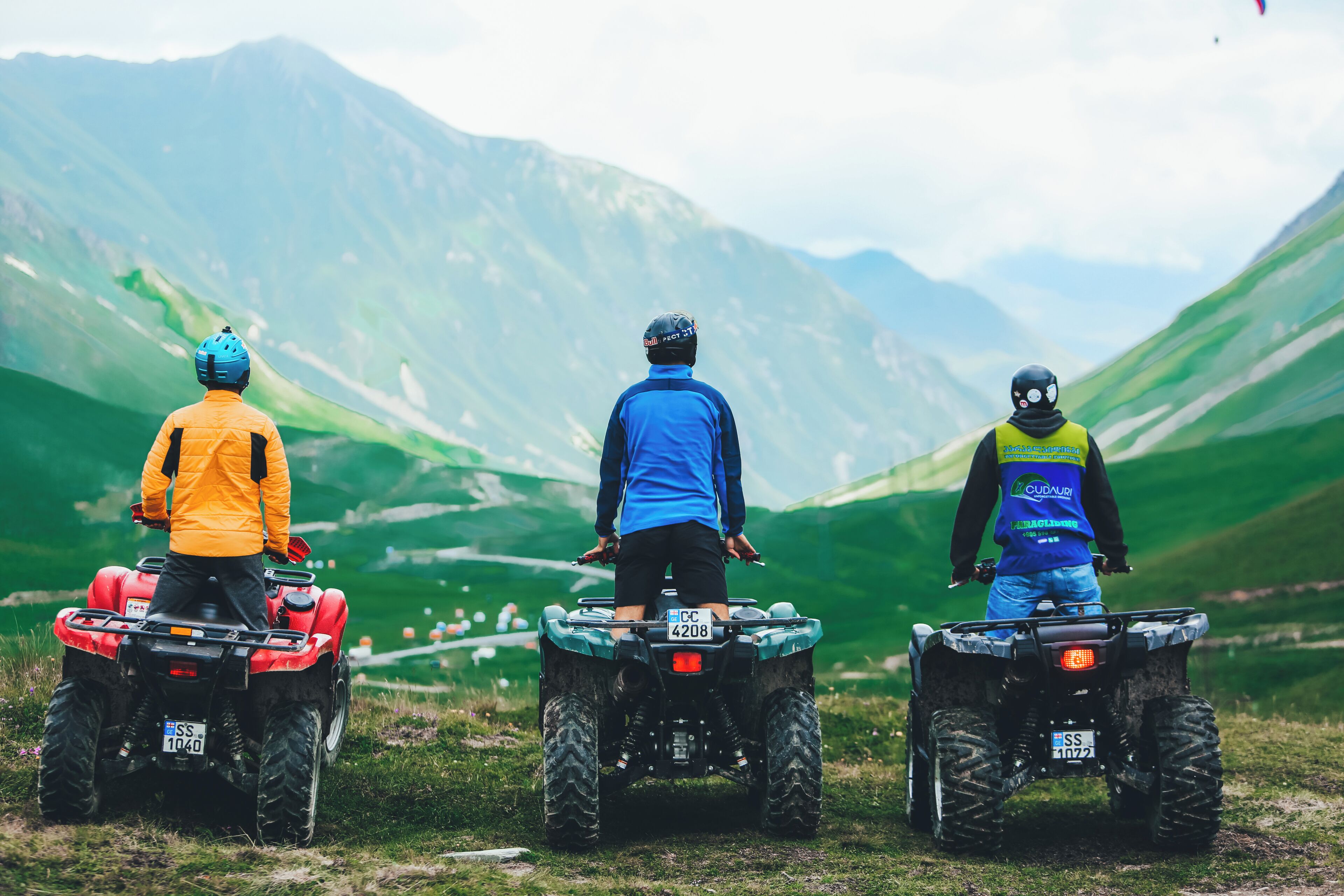Three people on ATVs in a mountainous area.