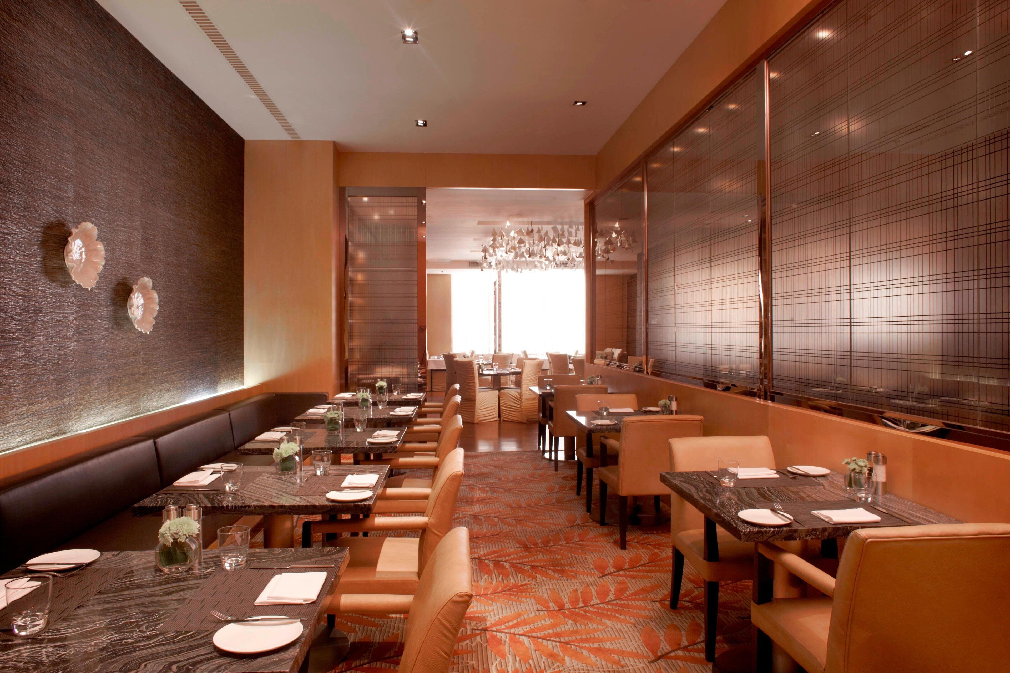 A restaurant with a long counter, booths, and tables, all set with tableware and glassware.