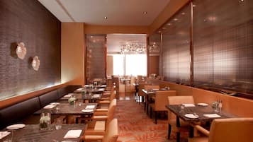 A restaurant with a long counter, booths, and tables, all set with tableware and glassware.