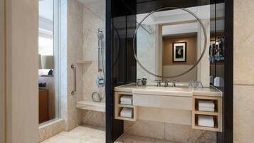 A modern bathroom with a large mirror, a shower, and a vanity with towel racks.